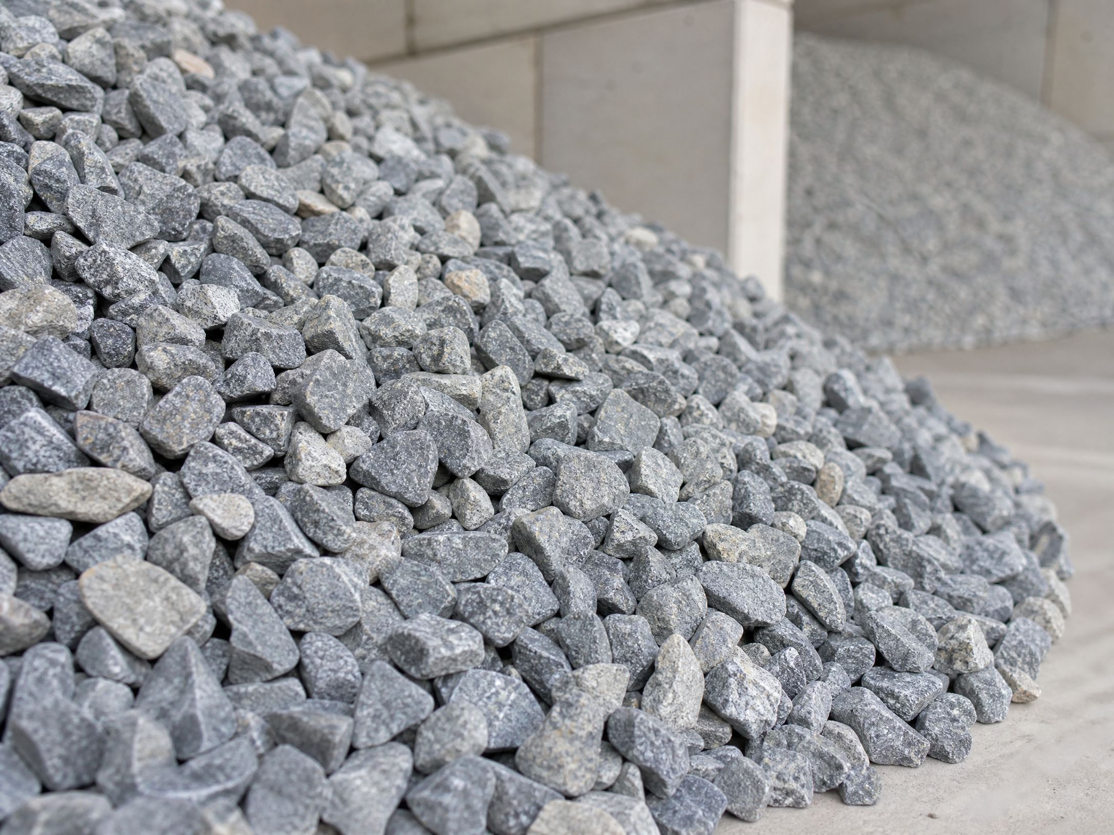 Piles of crushed gravel and construction aggregate on an industrial site.