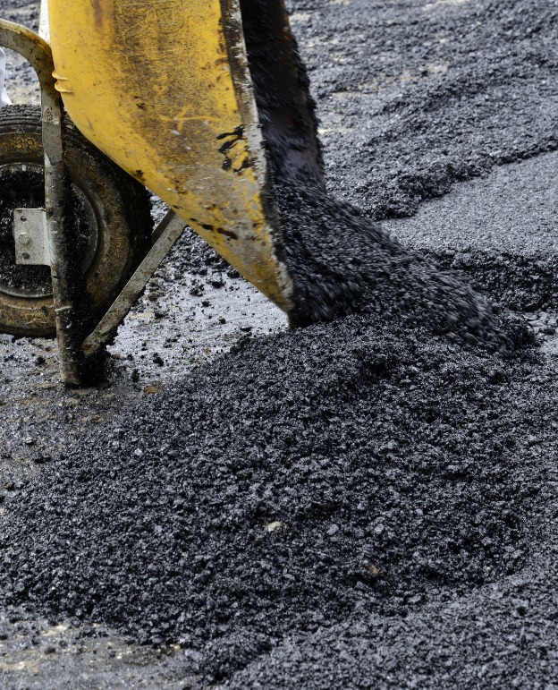 Construction site with heavy machinery and trucks on a dusty road.